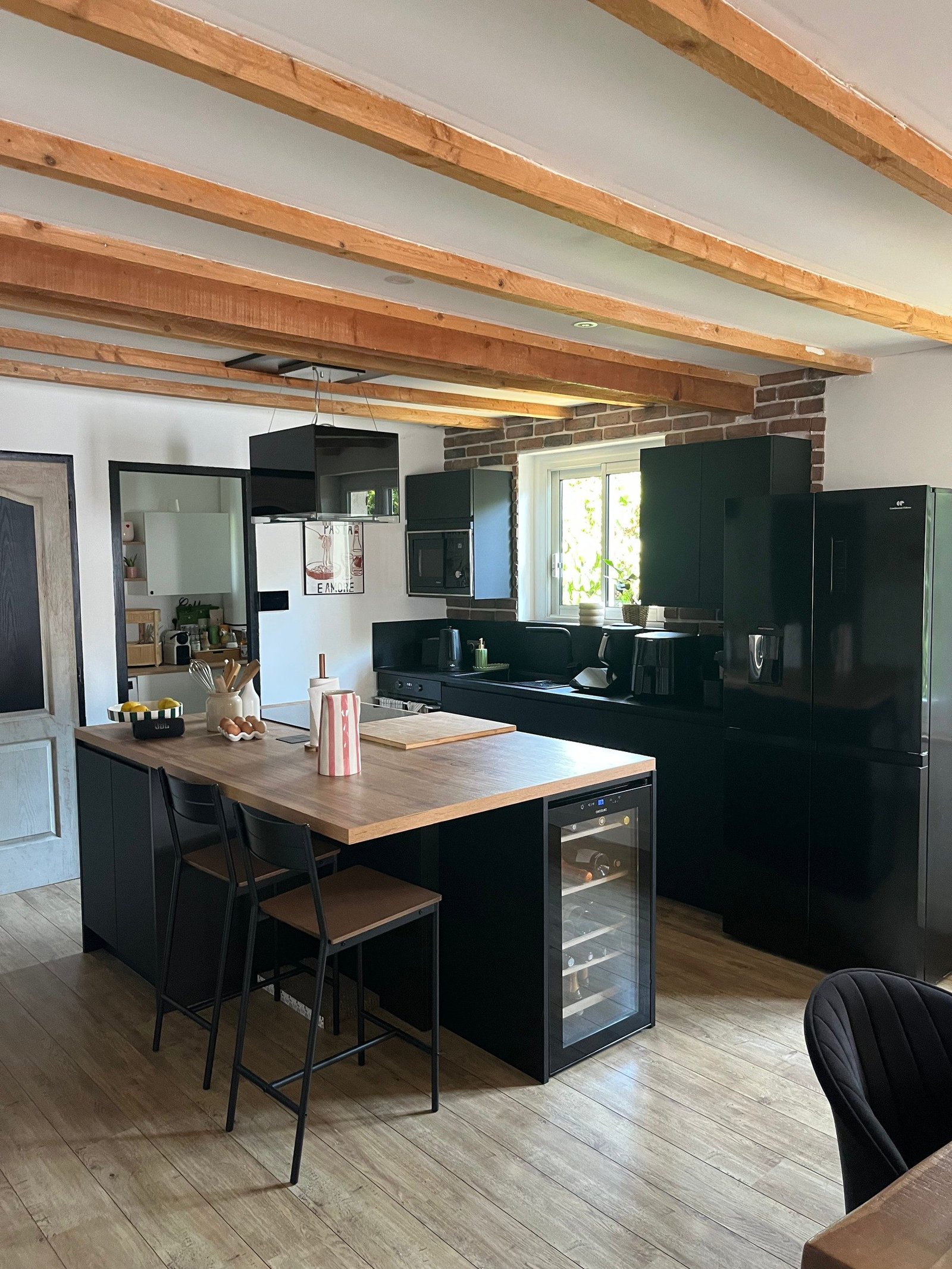 Vue d’ensemble de la cuisine noire et bois avec son îlot central