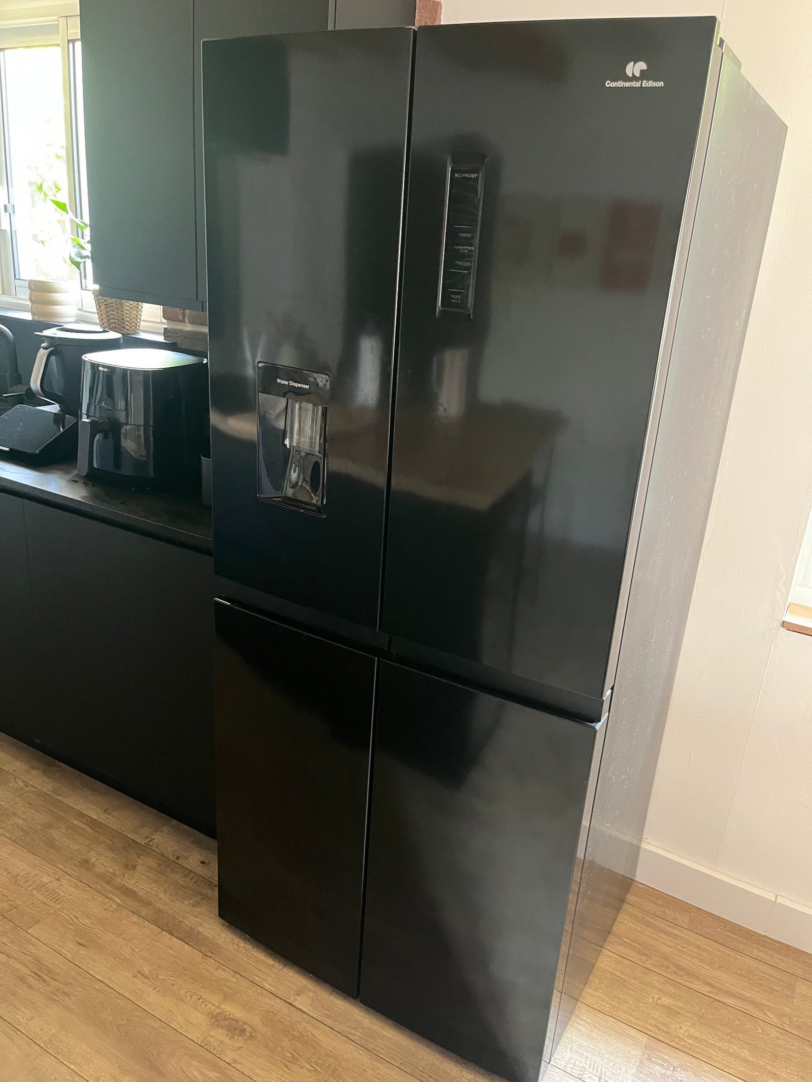 Réfrigérateur noir installé dans l’alignement des meubles de cuisine