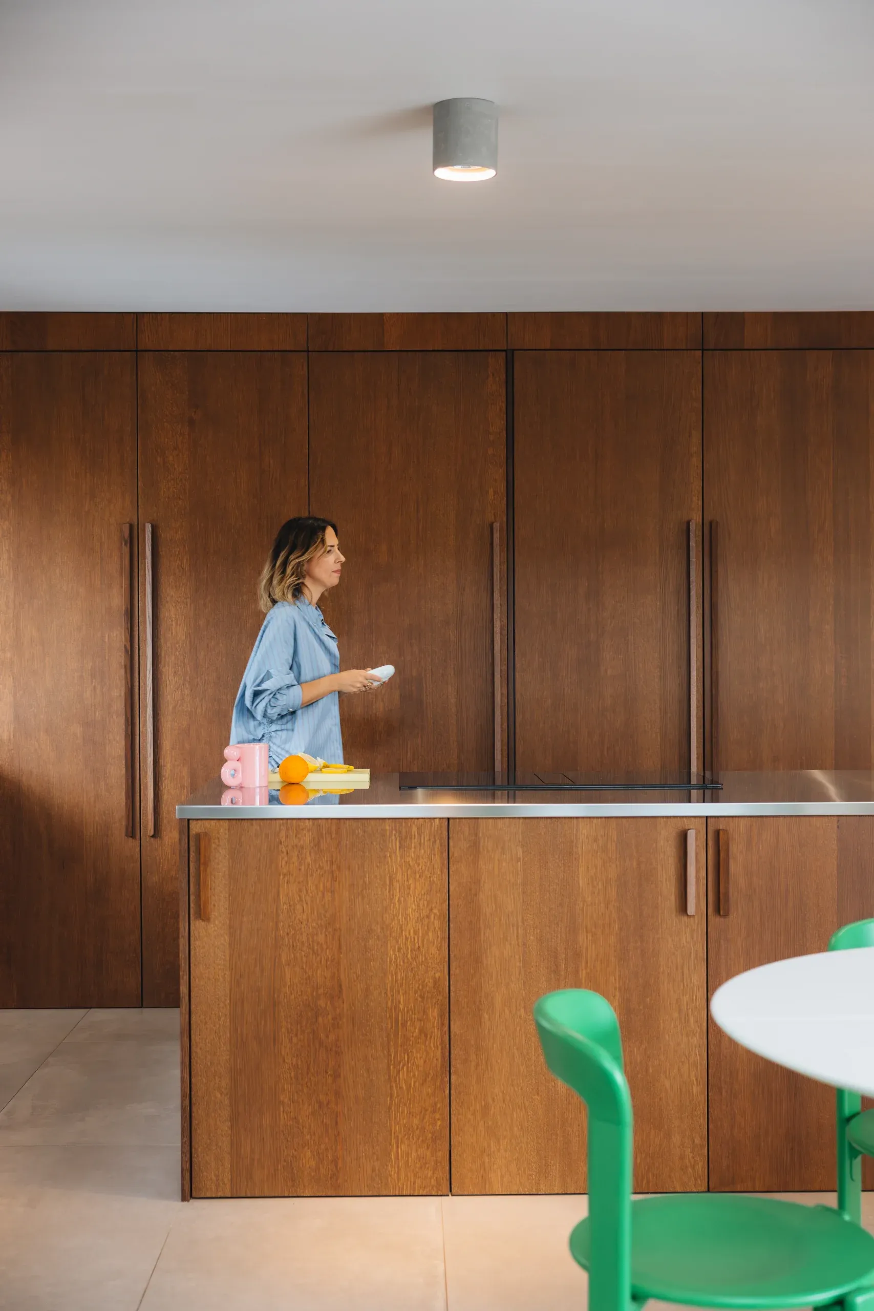 Cuisine teinte noyer — plan inox brossé visible, ambiance feutrée avec touches de couleur