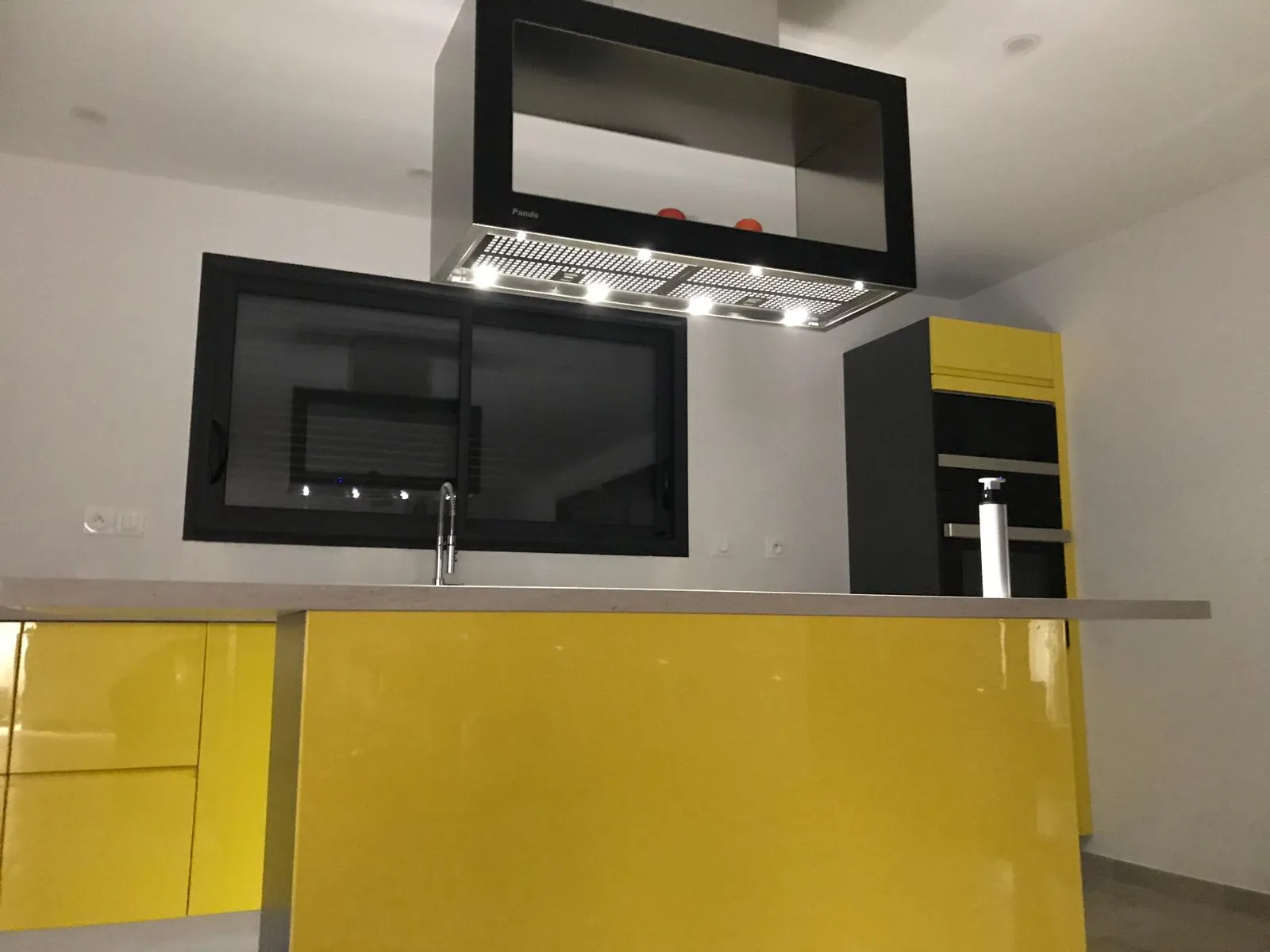 Cuisine jaune — détail de la hotte Pando inox et façades laquées vues de profil
